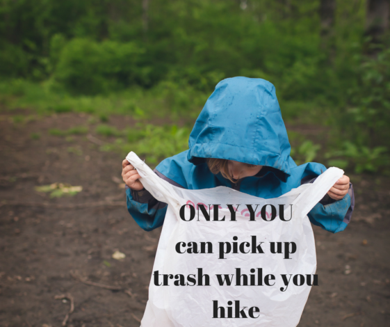 Child holding a garbage bag on a hike with the words "Only you can pick up trash while you hike"