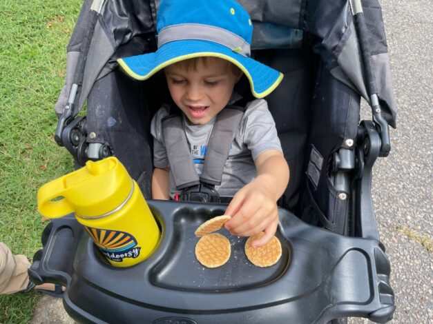 Child sitting in stroller eating mini waffles