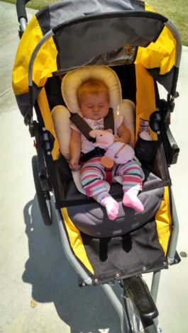 Young infant in jogging stroller with head support cushion