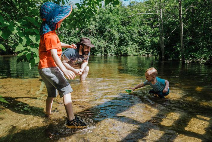 father and sons playing in shallow water