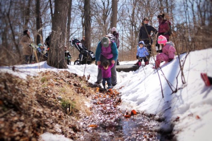 Hike it Baby group splashing in a snow bank/creek