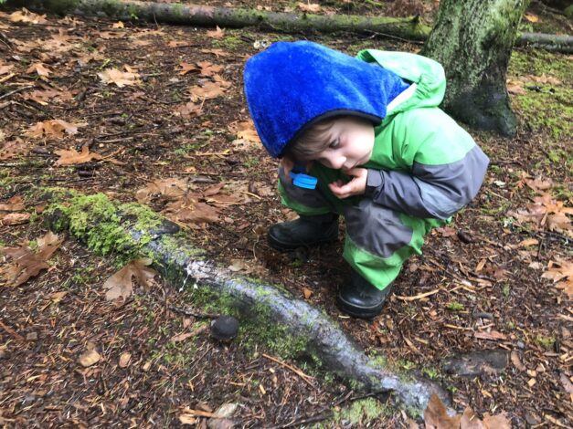 Child using magnifying glass to observe nature (Leave No Trace)