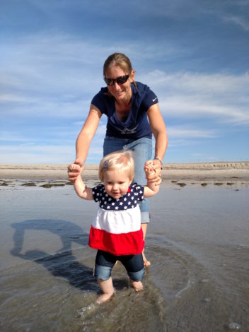Simple, Quick and Easy Outdoor Activities for Infants by Kirby Crawford for Hike it Baby (image of a mom and her baby girl practicing walking along a beach)