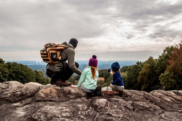 dad with two kids hiking with a mountain view