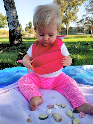 Simple, Quick and Easy Outdoor Activities for Infants by Kirby Crawford for Hike it Baby (image of a little girl eating apples on a picnic blanket)
