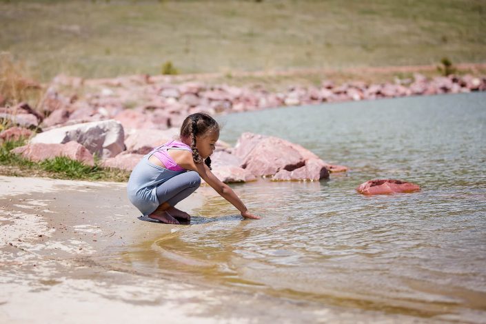 young girl playing on the sie of a lake