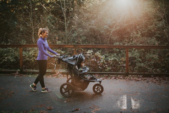 Mom pushing toddler in stroller on walking path