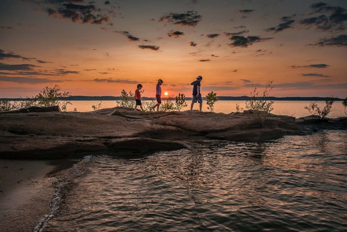 three boys hiking at sunset along the beach