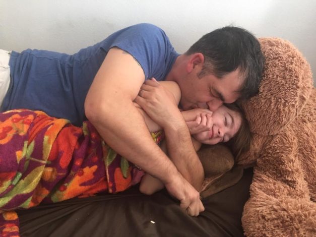 Man and his daughter cuddle on a couch