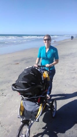 woman on beach with a joggine stroller using the infant car seat adapter