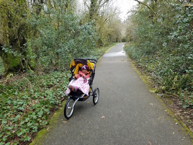 little girl in jogging stroller on paved path