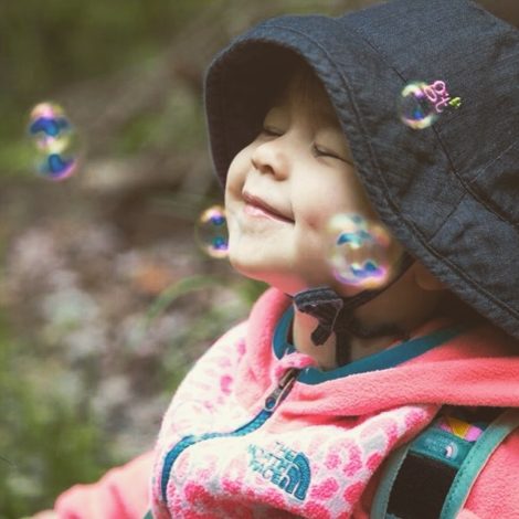 small girl smiling as bubbles float around her