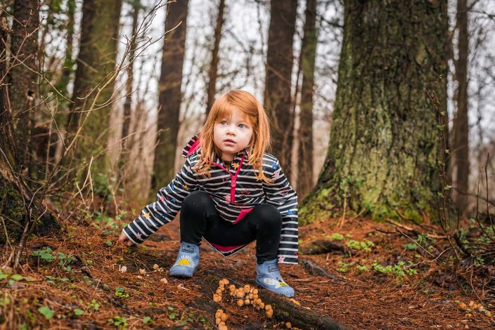 young girl in the woods wearing rain gear