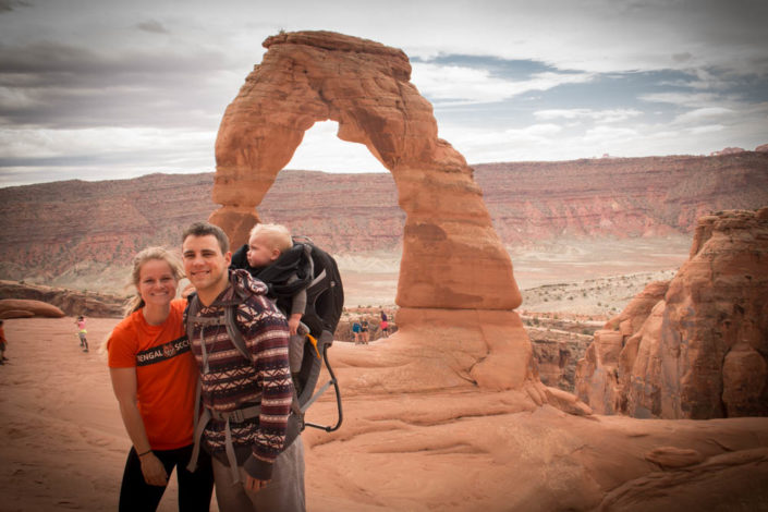 Couple with a child in a frame carrier standing in the desert of Moab 