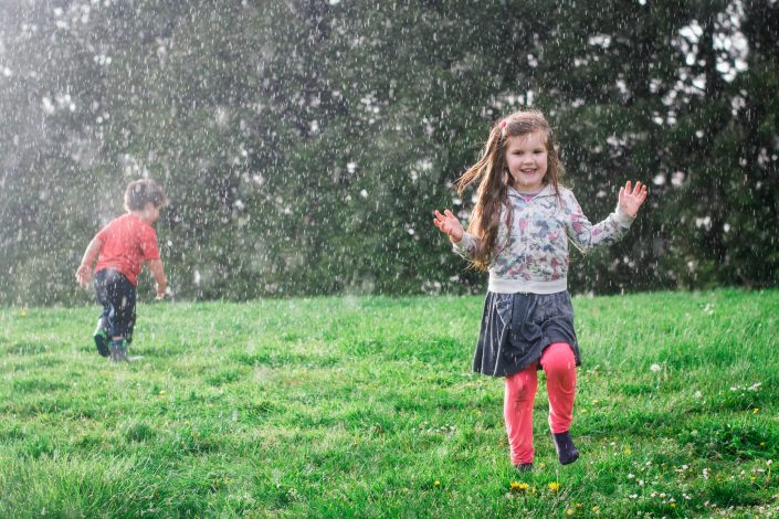 children playing in sprinker in the yard